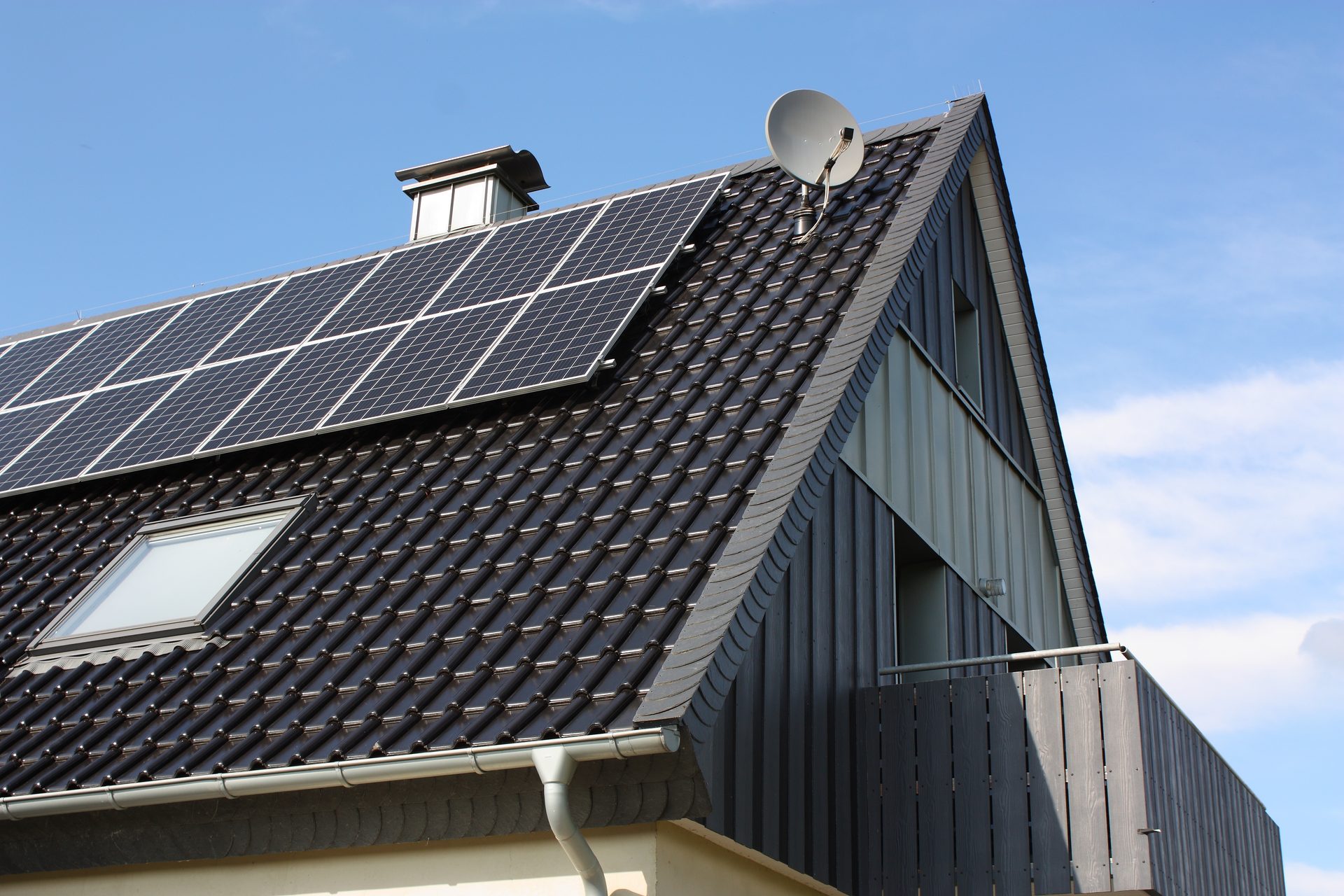 Solar array on a dark modern roof against a bright sky